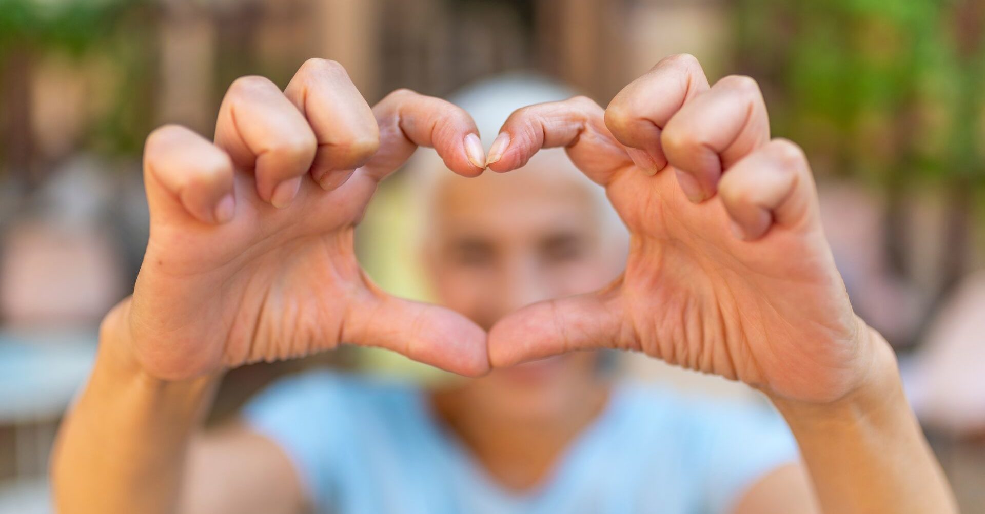 elderly lady making a heart with her hands