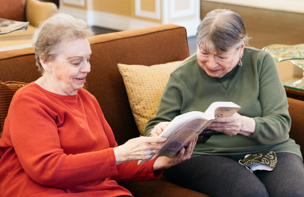 Two Ladies sitting on couch holding book together